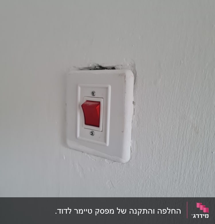 מתג חשמלי עם כפתור אדום על קיר לבן